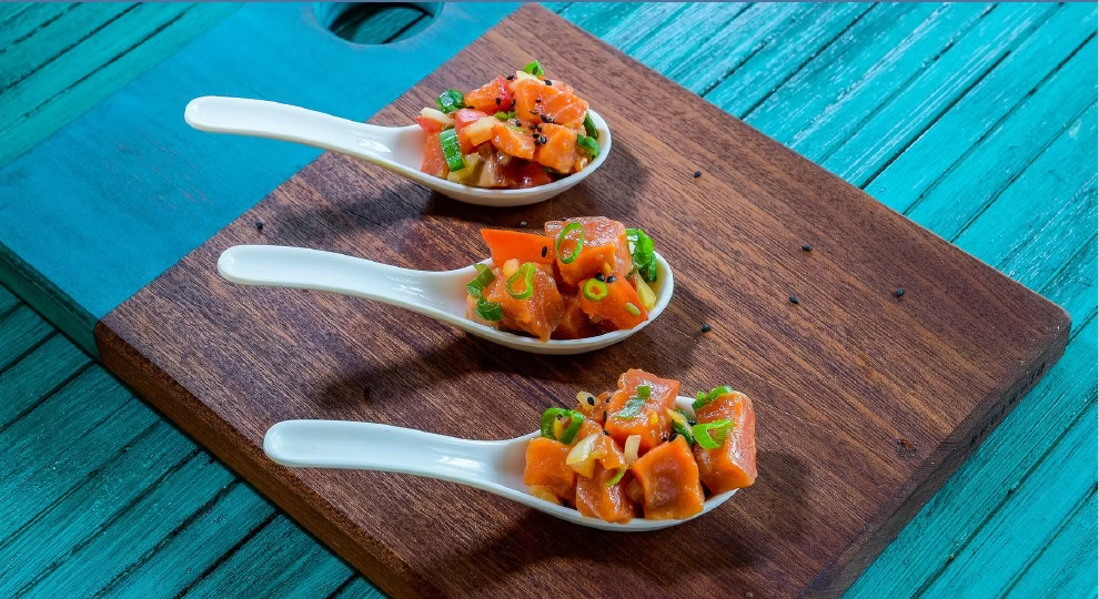 Three white Japanese soup spoons with scoops of Copper River sockeye lomi lomi.