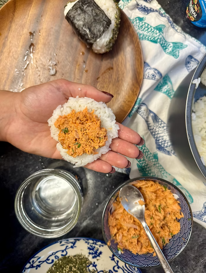 Salmon and rice ball on open palm over fish printed towel