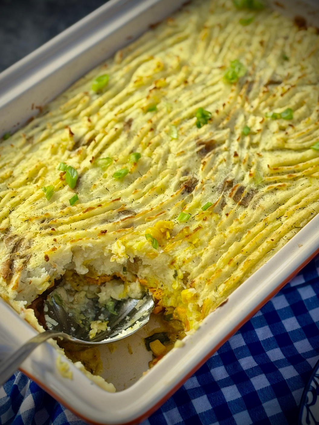 The baked fisherman’s curry pie with a golden mashed potato topping, partially scooped to reveal the salmon and vegetable curry filling underneath.