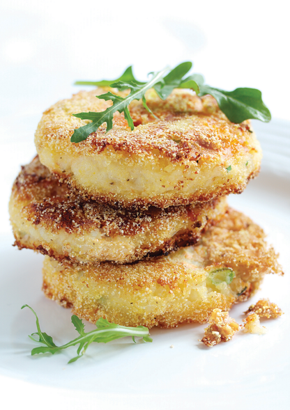 Stack of fried minced halibut garnished with arugula on a white background