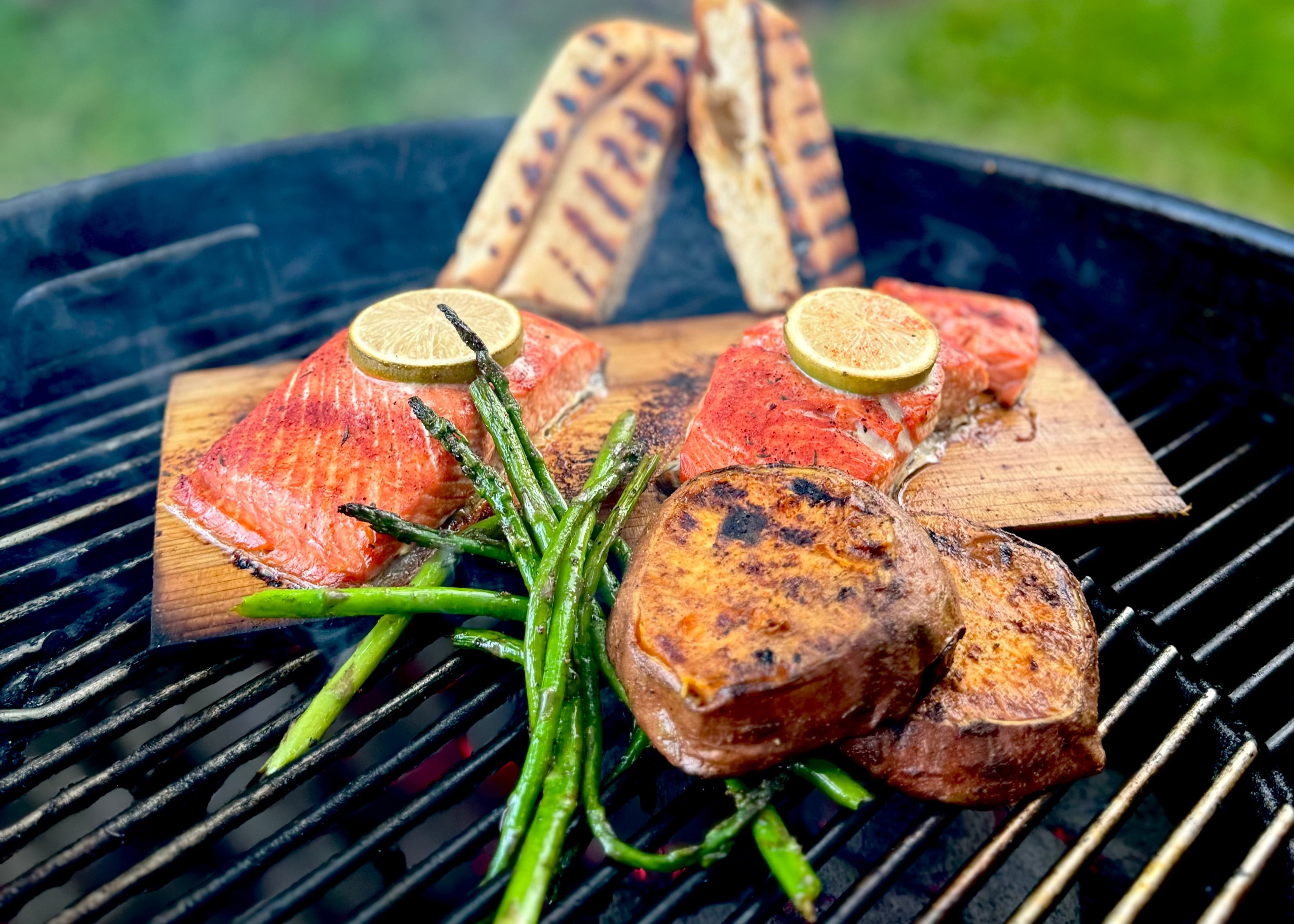Grilled salmon with asparagus on a barbecue grill outdoors.