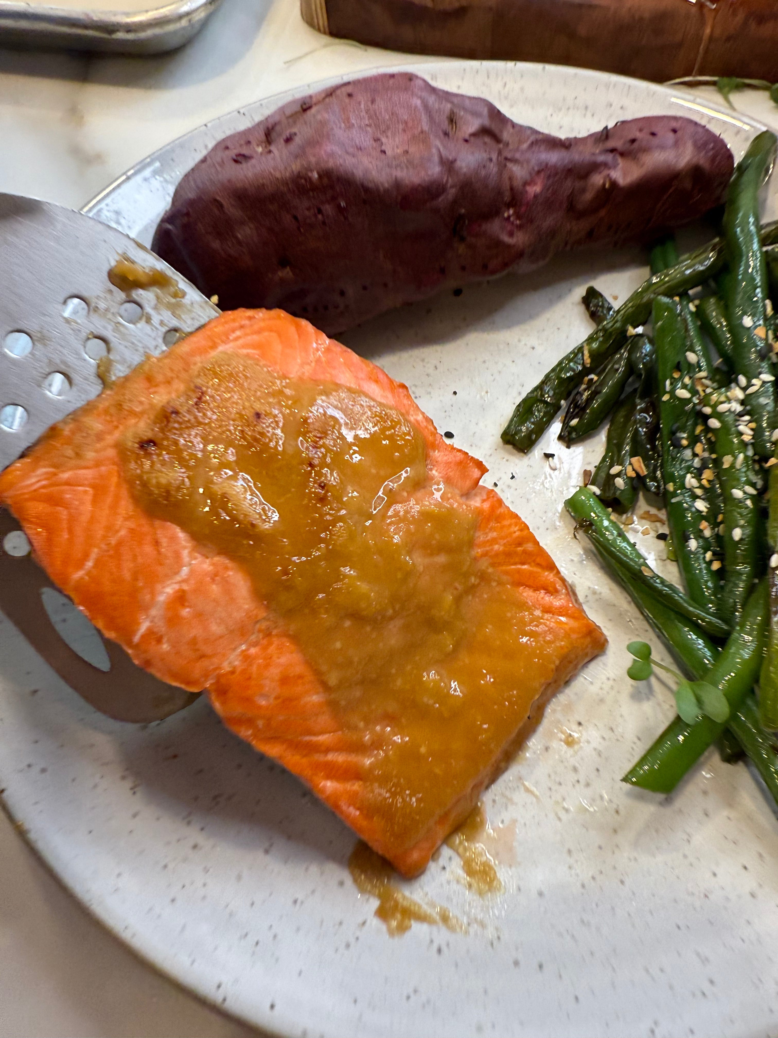 Plated dish with salmon, sweet potato, and green beans on a white plate.