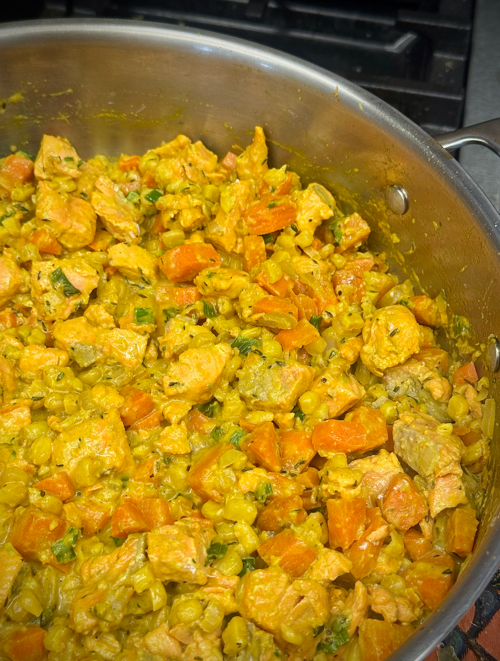 Close-up of the fisherman’s curry pie filling, showing chunks of salmon mixed with potatoes, carrots, peas, and corn in a lightly spiced golden curry sauce.