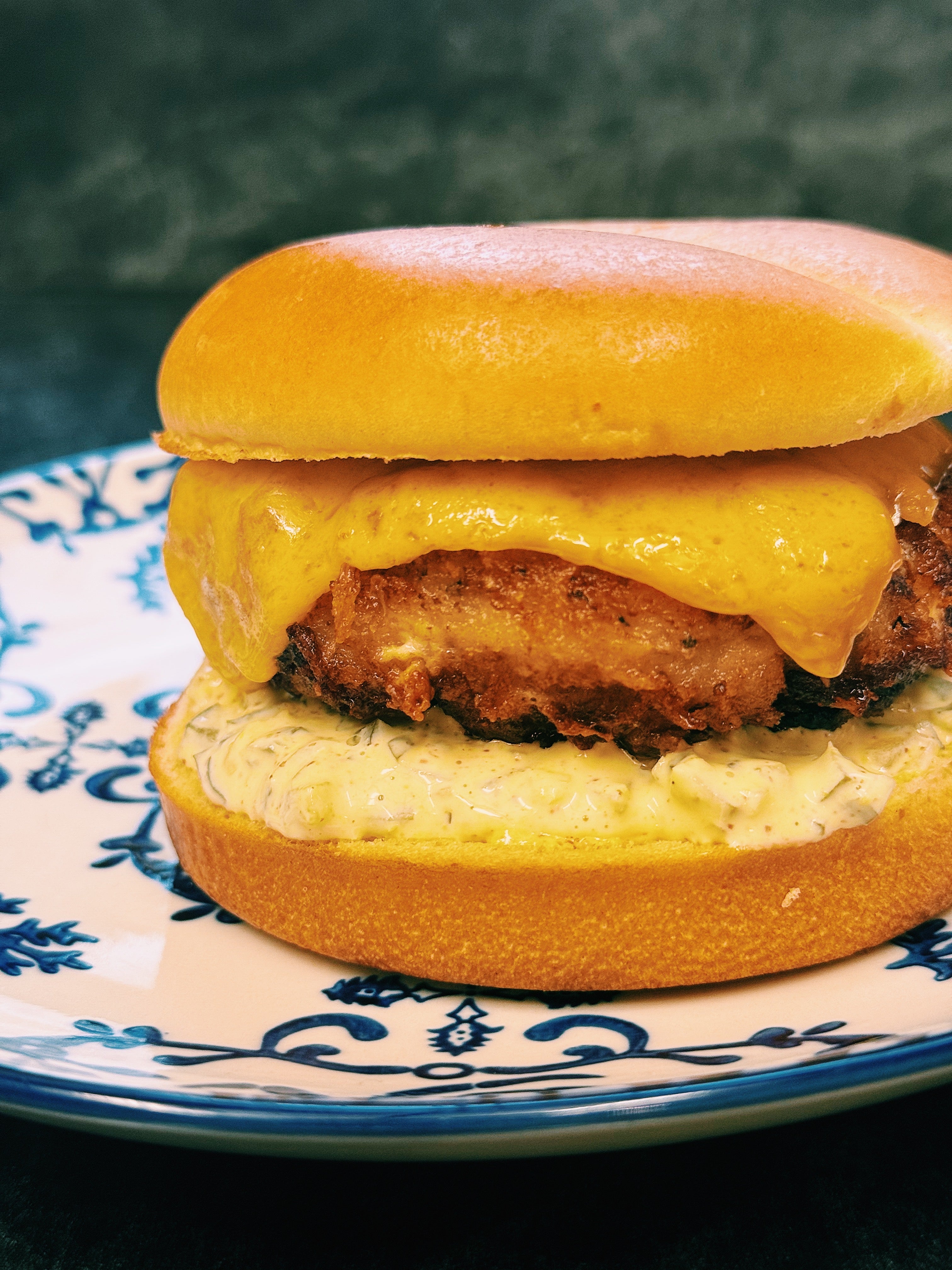 Minced halibut burger with cheese and sauce on a decorative plate