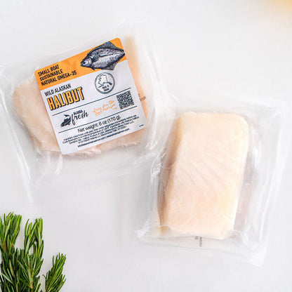 Two packages of halibut, accompanied by a sprig of rosemary.